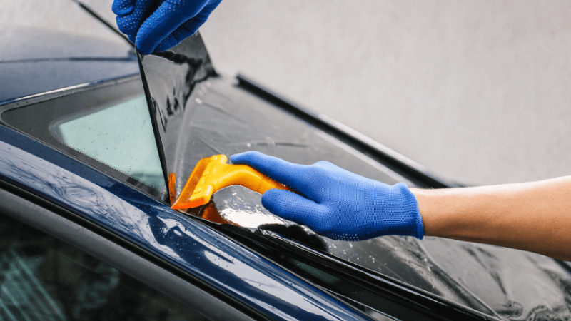 A man is applying a car window tint.