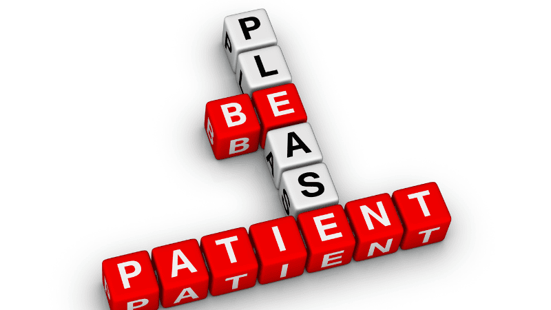 Some small squares printed with letters make up the sentence "PLEASE BE PATIENT"