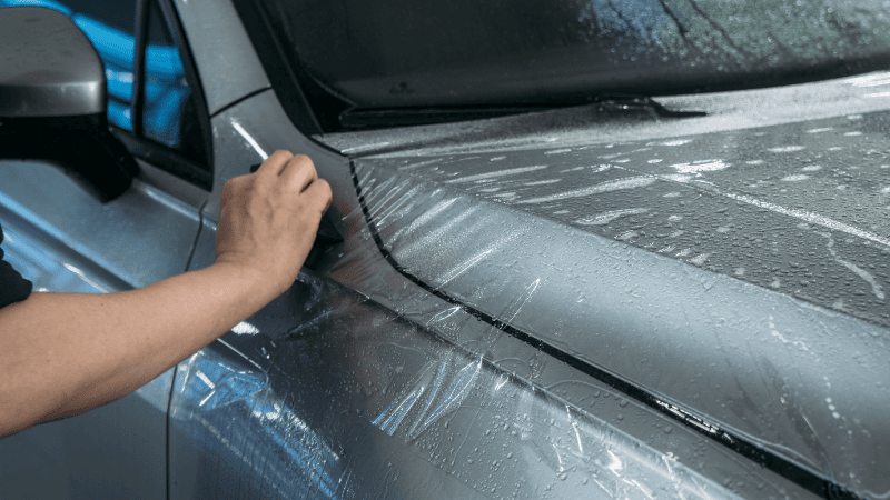 A man is installing a PPF on the car.
