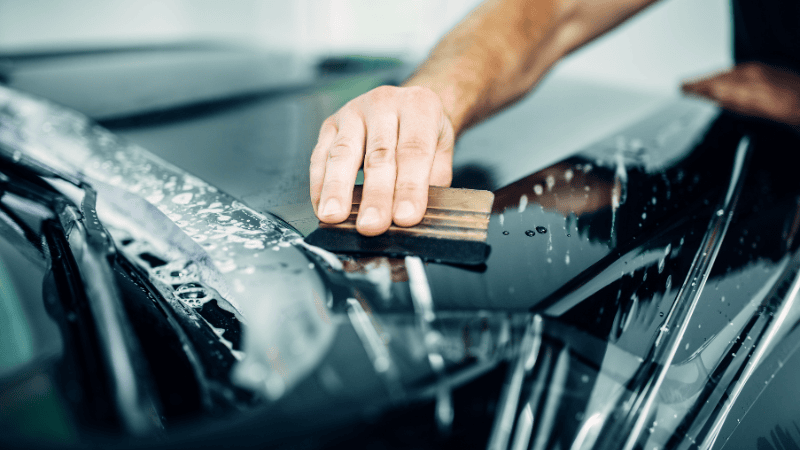 A man is installing a PPF on the car.