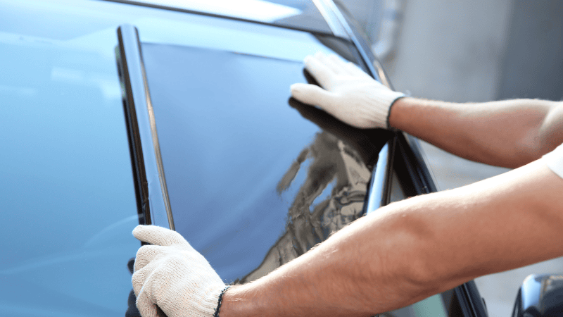 A man is installing a window tint film on the car.
