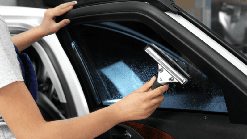 A girl is installing a window tint film on the car.