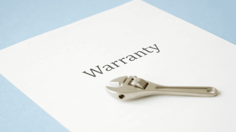 There is a wrench on a piece of white paper printed with "Warranty".