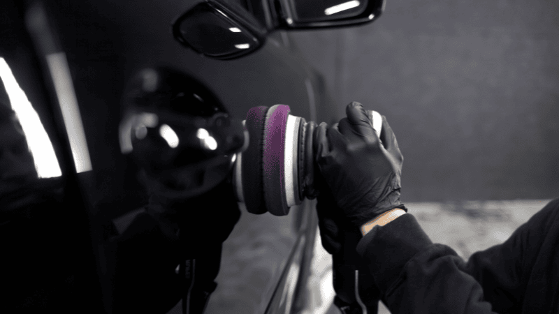 A man is waxing the car.