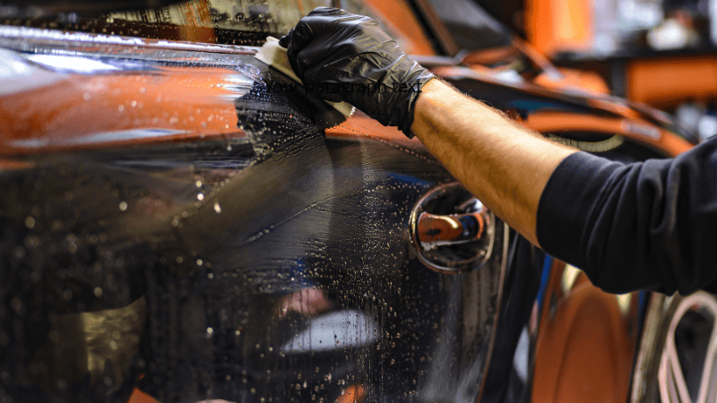A man is cleaning the car with a microfiber cloth.