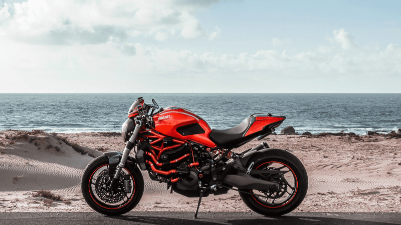A motorbike is parked by the seaside.