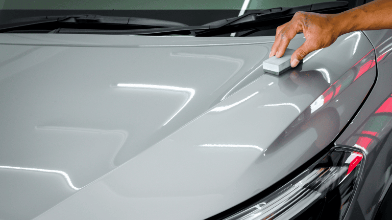 A man is painting a ceramic coat on the car.
