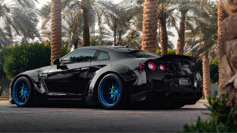 A black sports car is parked in the shade.