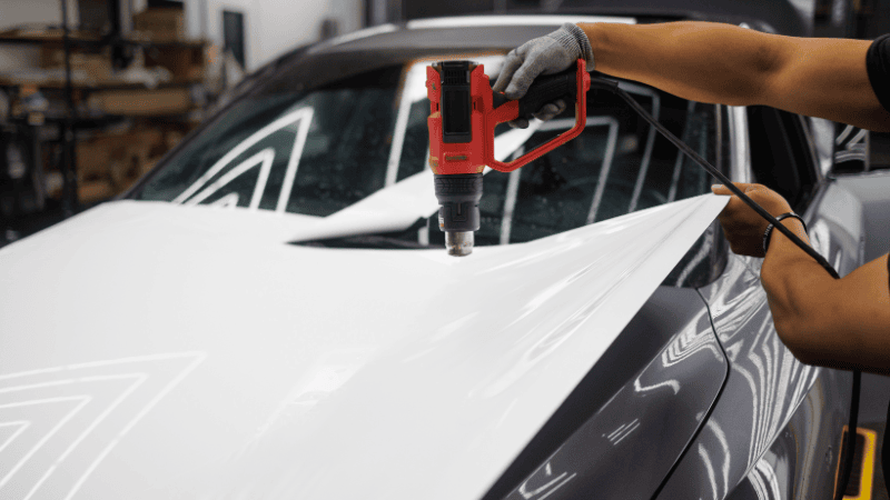 A man is wrapping a car with a heat gun.
