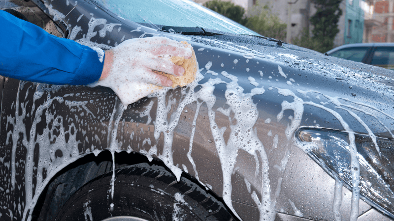 A man is washing the car by hand.