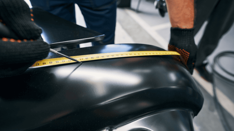 A man is measuring the length of the car.