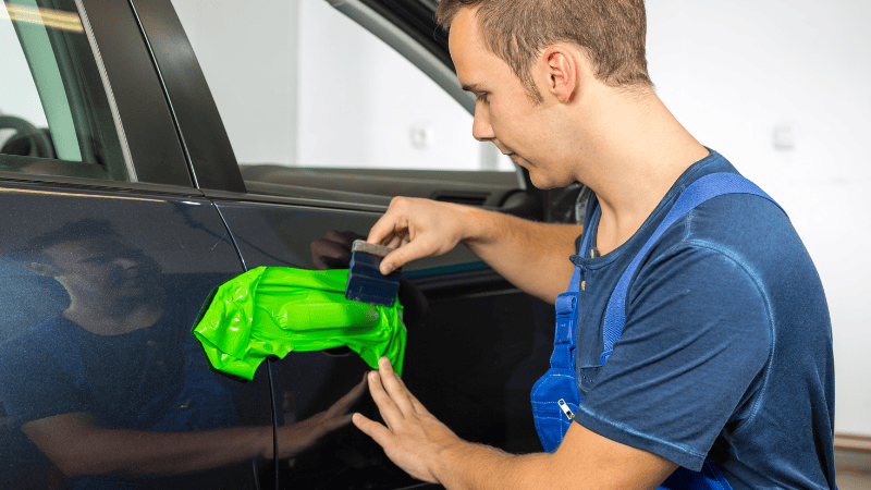A man is wrapping the car's doorknob.