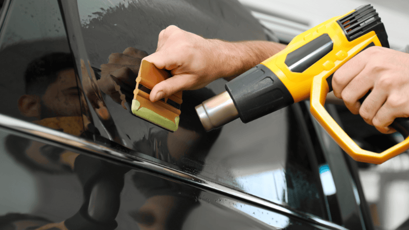 A man is heating the car wrap with a heat gun.