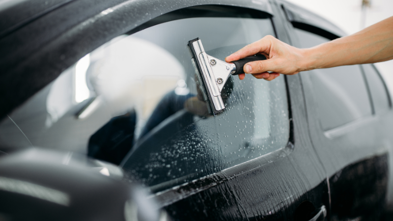 A man is cleaning the car window.