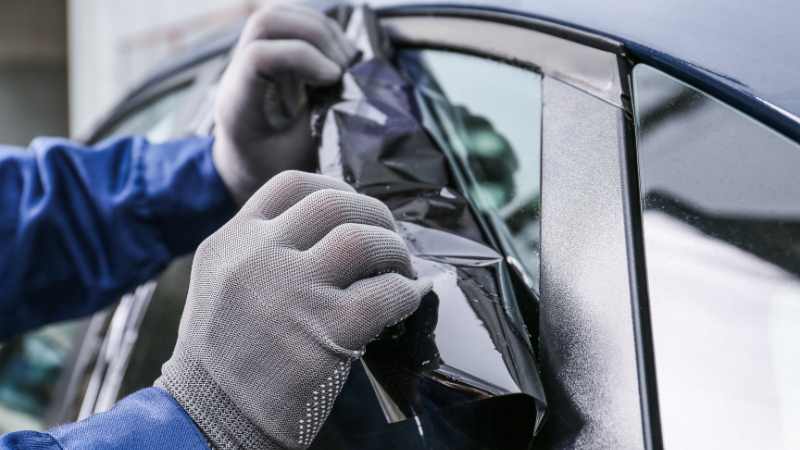 A man is removing the car window tint.