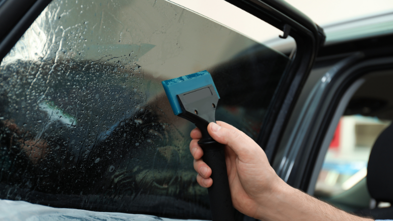 A man is applying the car window tint.