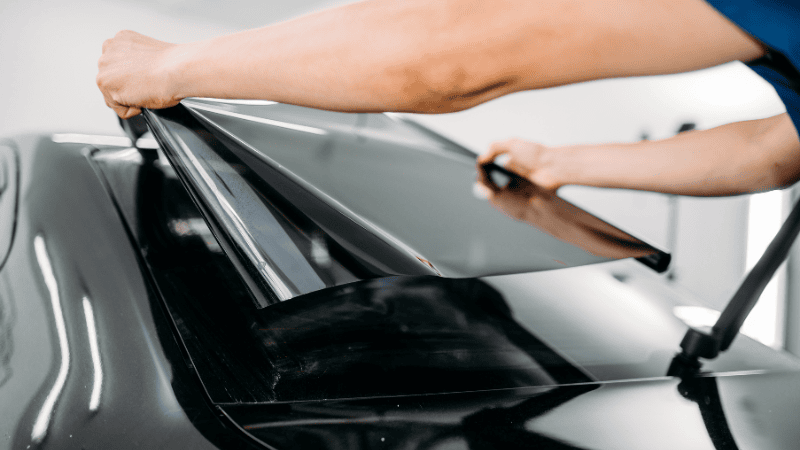 A man is applying a car window tint film.
