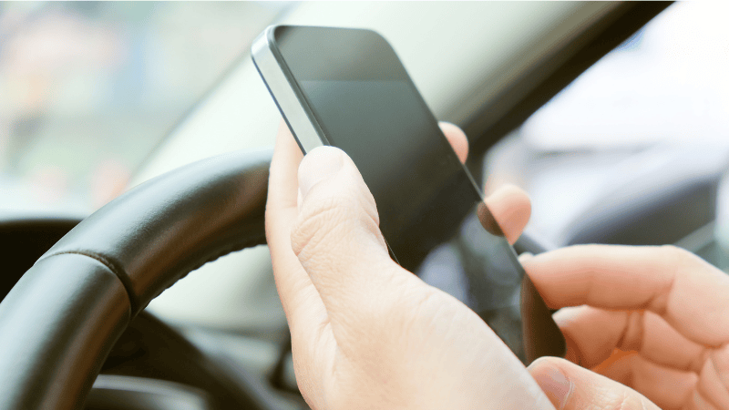 A man is playing with his phone in the car.