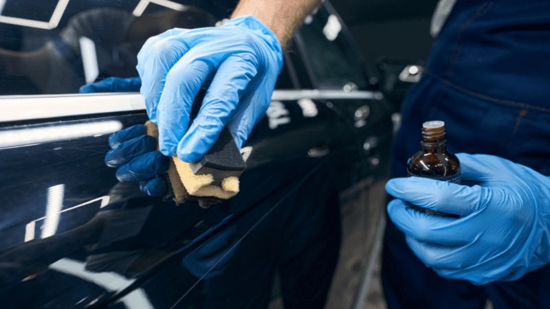 Close-up of a professional applying ceramic coating to a car's surface