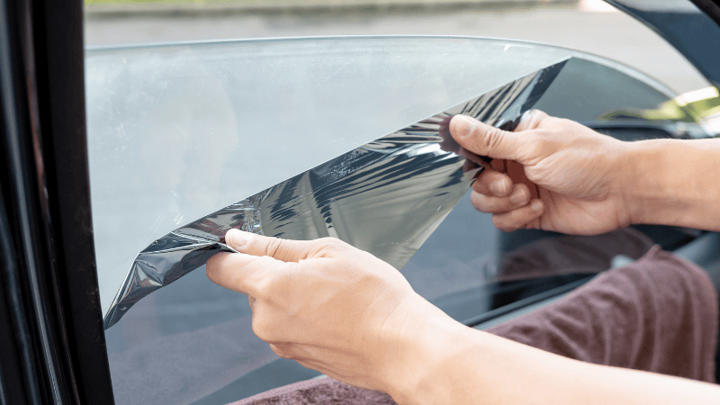 A man is removing the car window tint film.