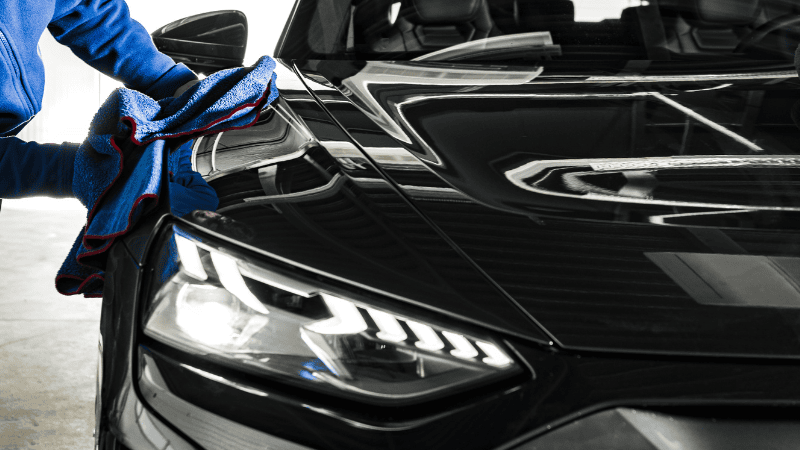A man is wiping the car with a microfiber cloth.