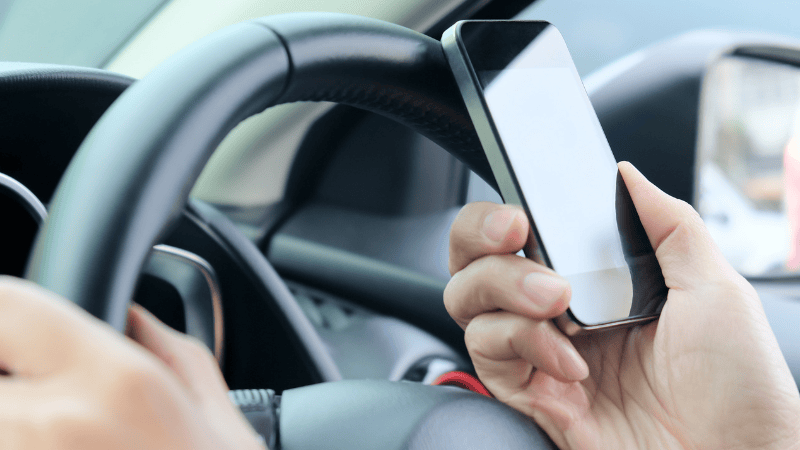 A man is using the phone in the car.