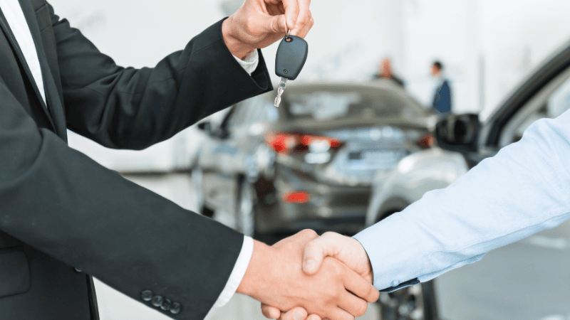 Two men completed the car transaction and are shaking hands.
