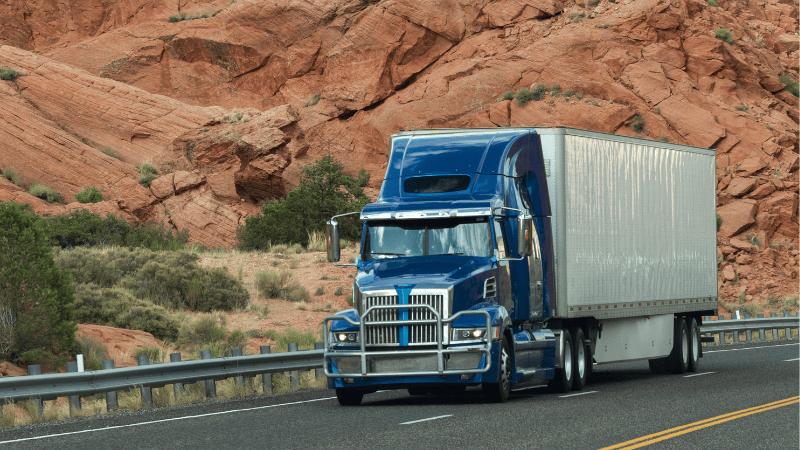 A truck is driving on the road with many small rocks.