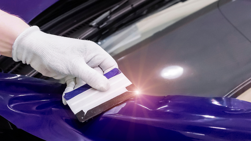 A man is wrapping the car window trims.