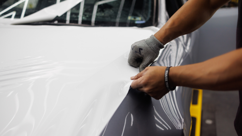 A man is sticking the car wrap to the car's surface.