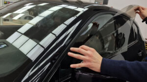 A man is installing a car window tint film.