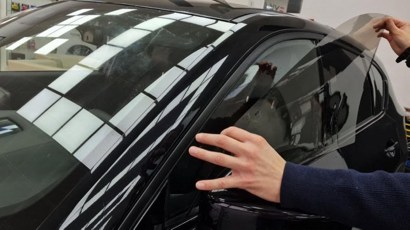 A man is installing a car window tint film.