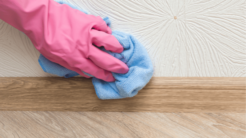 A man is cleaning the wall by using a soft cloth.