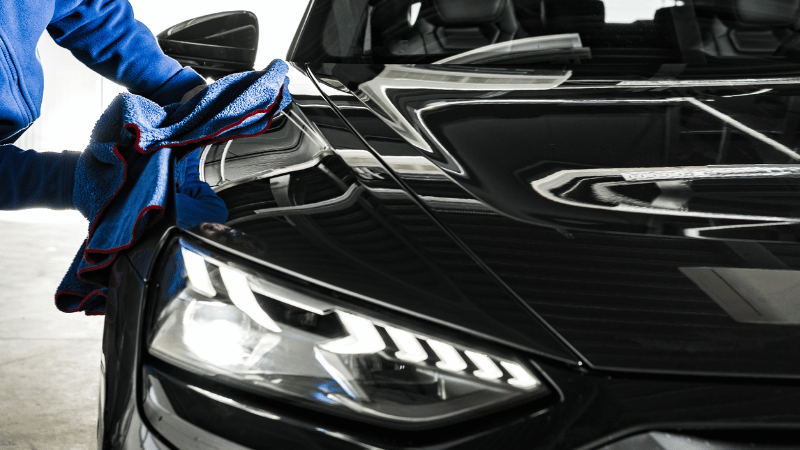 A man is wiping the car with a microfiber cloth.