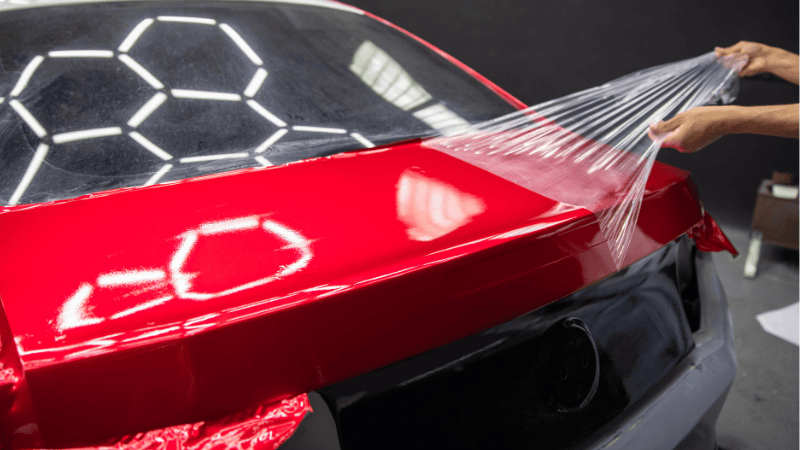 A man is removing the vinyl wrap from the car