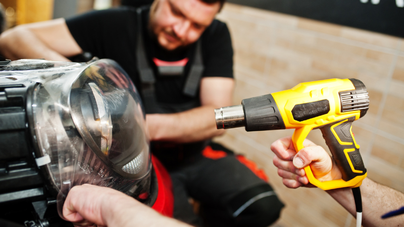 A man is using a heat gun to apply the PPF.
