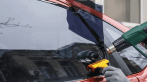 The man is tinting the car window.