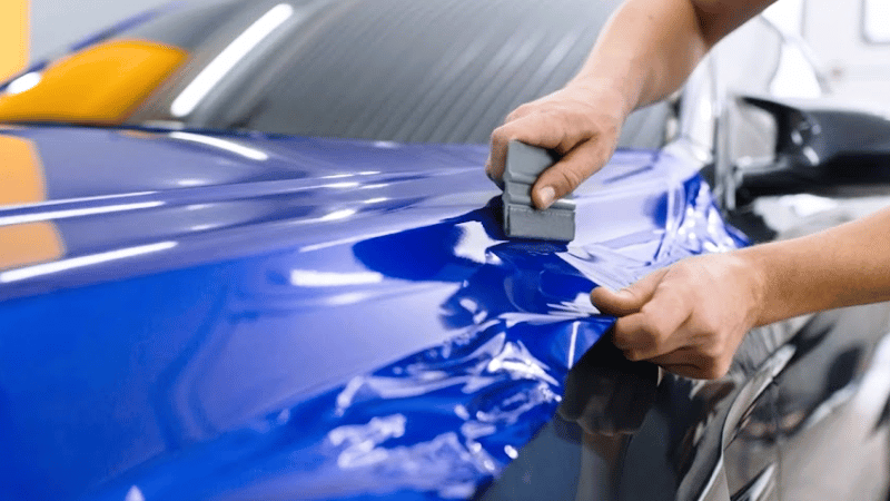 A man is applying the car vinyl wrap.