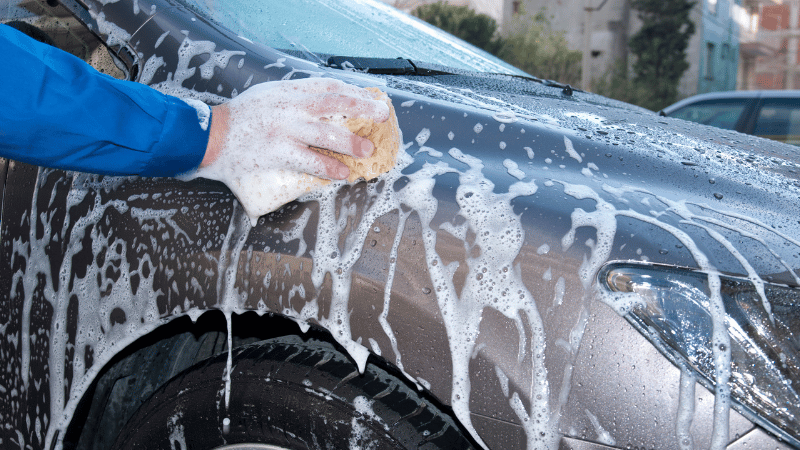 A man is washing the car by hand.