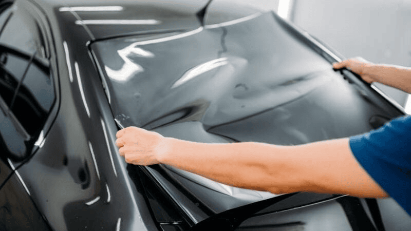 A man is applying the car window tint film.